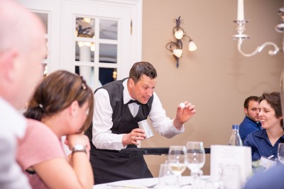 Sir Julian mit einem Bechertrick an einem Tisch