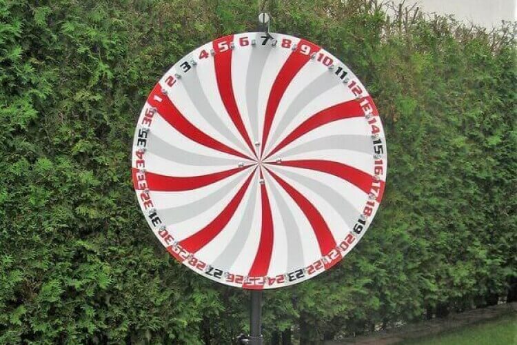 Glücksrad vor einer Hecke