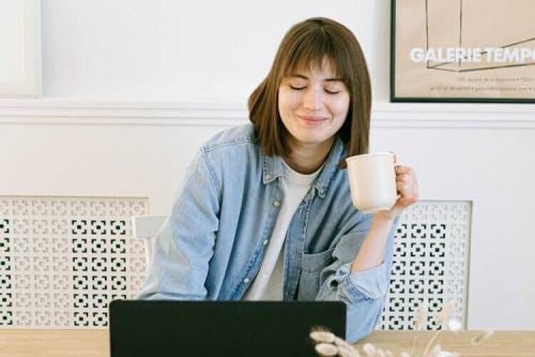 Frau mit Kaffeetasse und Laptop
