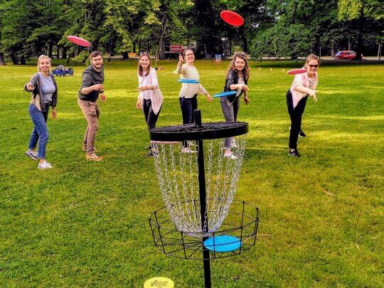 Personen spielen beim Teamevent Frisbeegolf im Park in Leipzig
