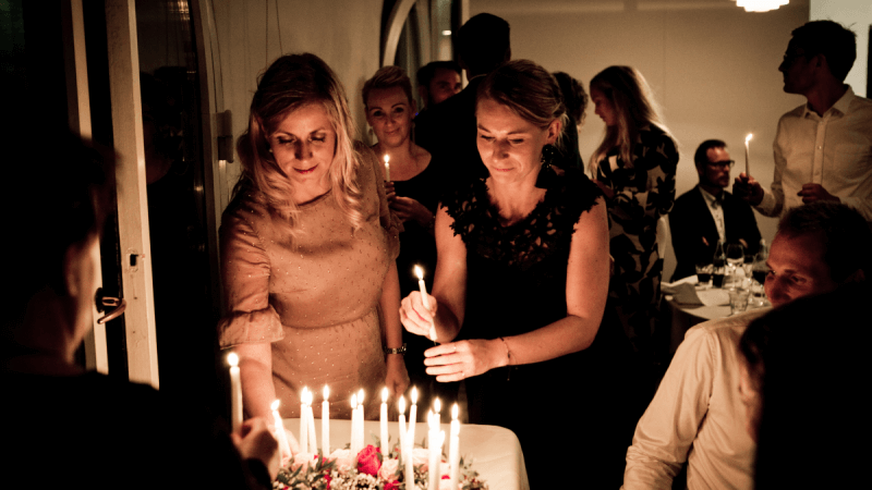 Frauen zünden Kerze auf Geburtstagstorte an