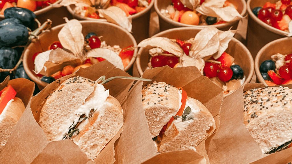 Sandwiches und Obstsalat in umweltfreundlichen Tüten und Schälchen