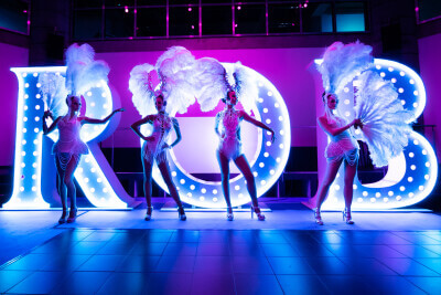 Dreamotionz Showtänzer im herausragenden Glamour- Federlook präsentieren die Inschrift der Robinson Camyuva