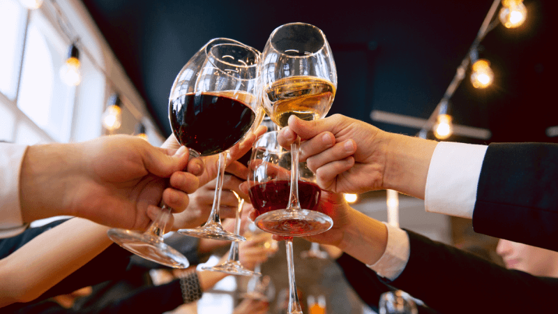 Halbvolle Weingläser, mit denen angestoßen wird