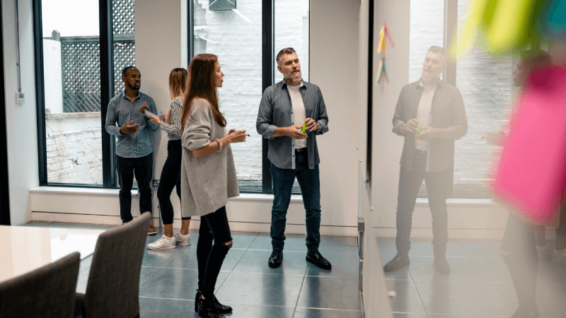 Personen stehen vor einem Whiteboard in einem Workshop-Raum
